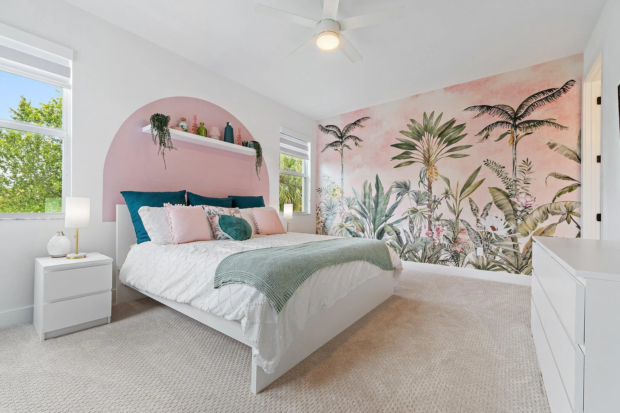 Bedroom with tropical palm tree mural and arched upholstered headboard