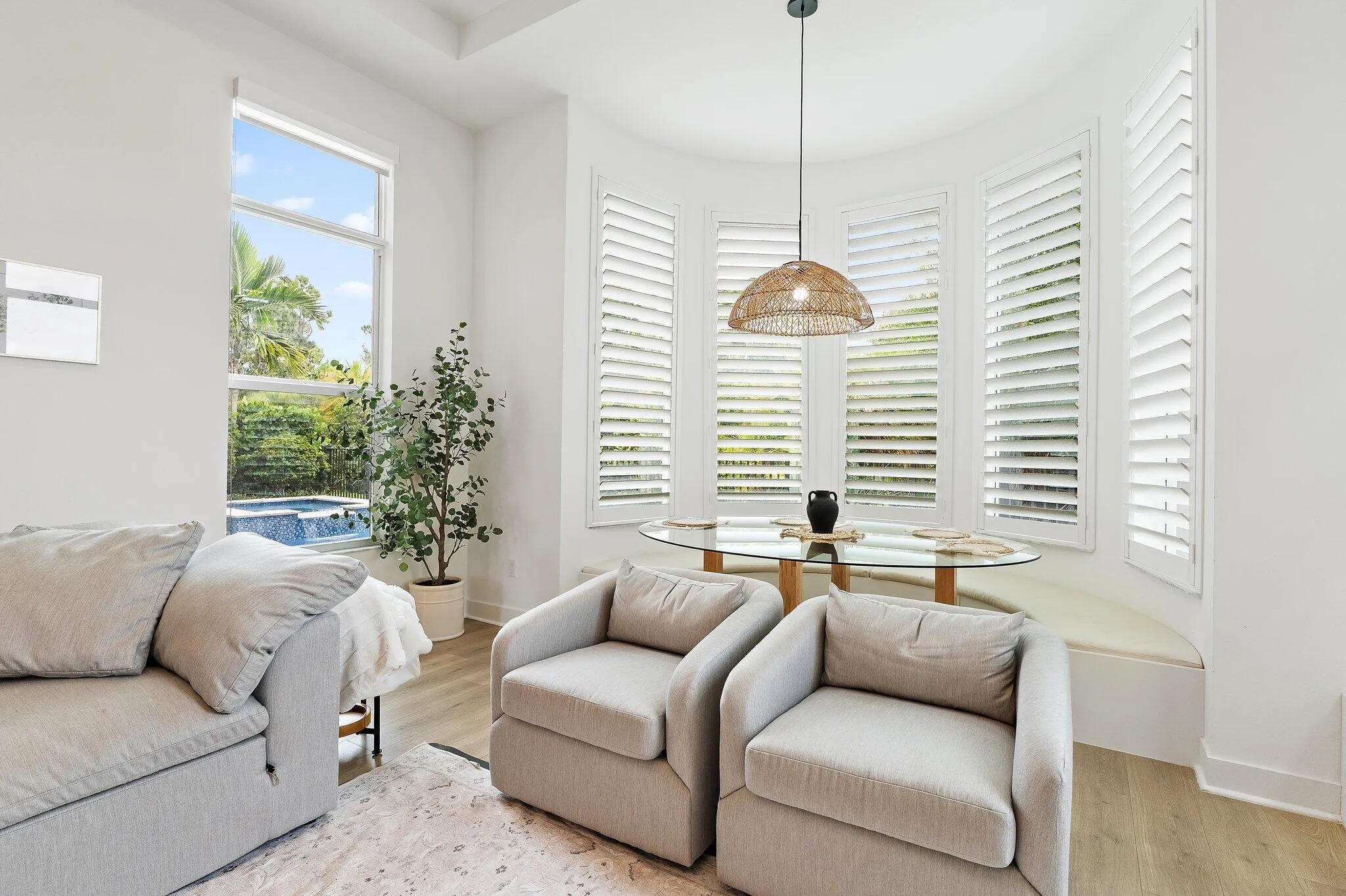 Sitting nook with bay window, armchairs, plantation shutters, and pool view