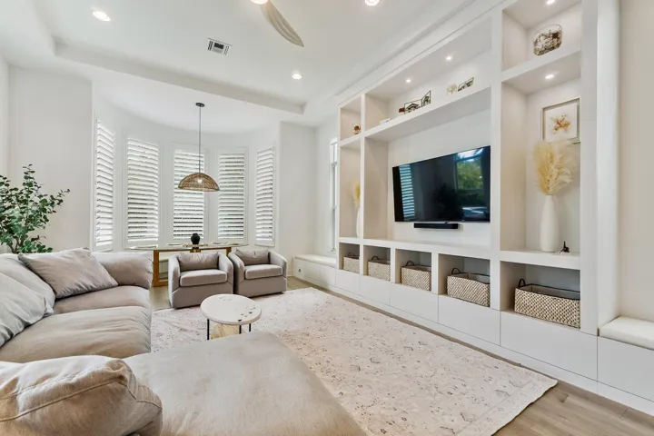 Family room with sectional sofa, built-in shelving, mounted TV, and plantation shutters