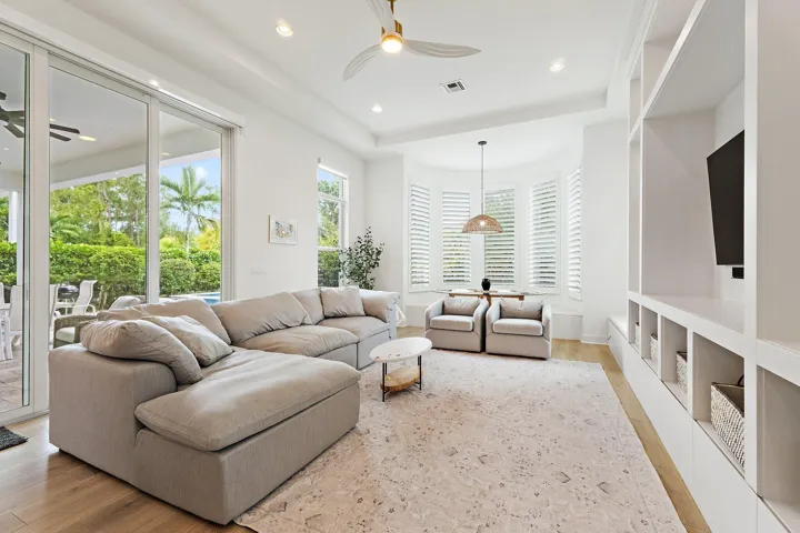 Living room with sectional sofa, mounted TV, built-in shelving, and French doors to outside