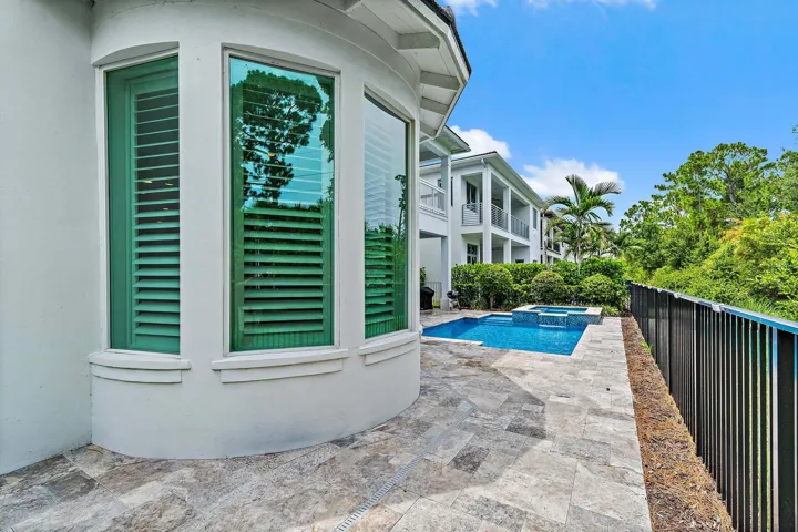 Exterior detail with plantation shutters, black fence, and pool