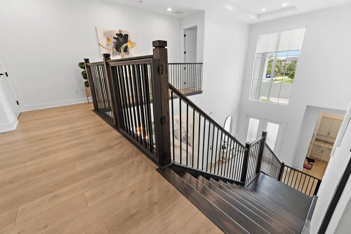 Upstairs landing with wood staircase and black iron railing