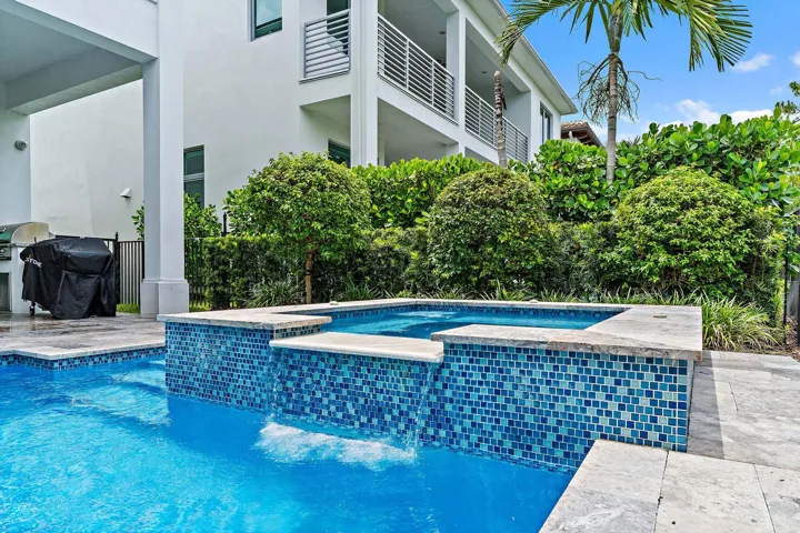 Backyard pool and spa with tiled accents and outdoor kitchen