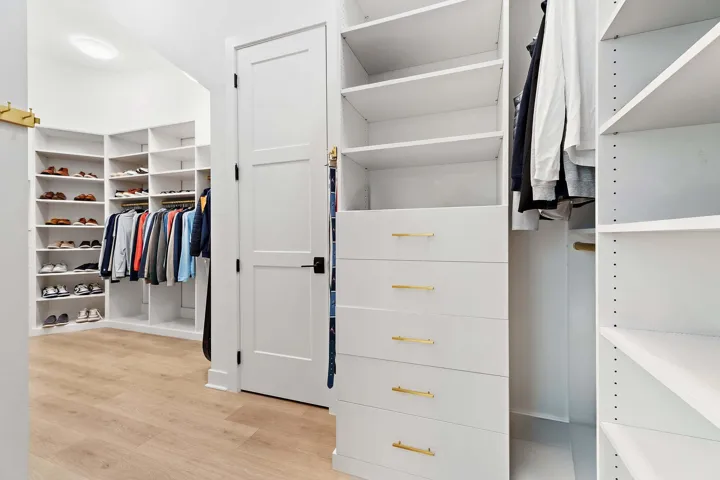 Walk-in closet with white built-in shelving and drawers