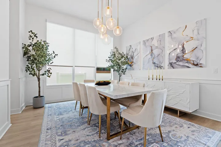 Dining room with wood table, upholstered chairs, artwork, and area rug