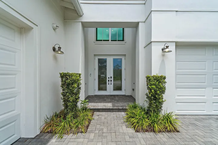 Covered front entry with glass door and manicured landscaping
