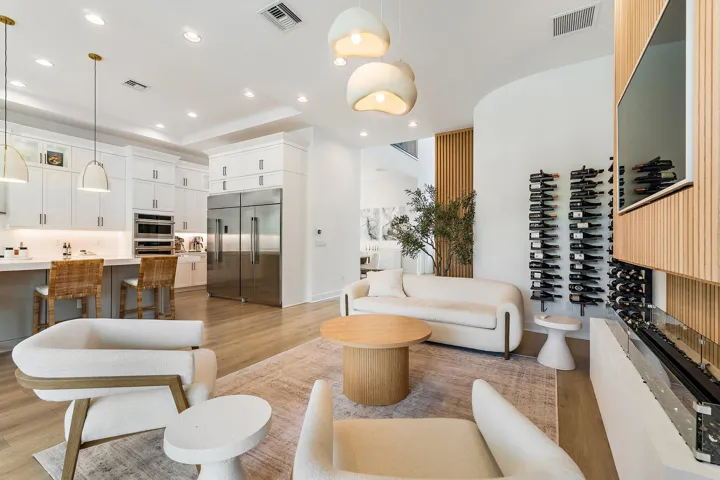 Sitting nook with swivel chairs, round side table, and wine display shelving near kitchen