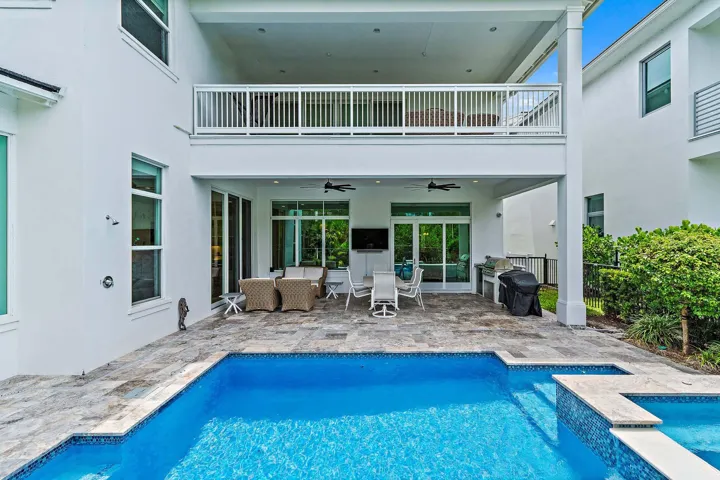 Rear exterior with pool, covered patio, and second-story balcony