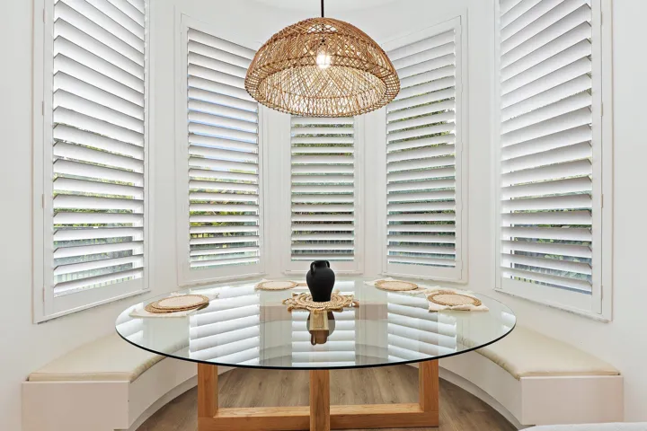 Breakfast nook with round glass table, built-in bench seating, and bay window