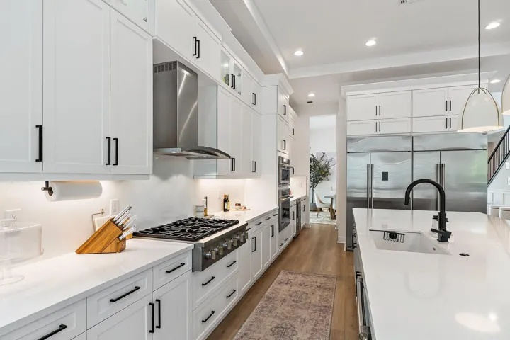 Kitchen with marble backsplash, professional-style range hood, and farmhouse sink