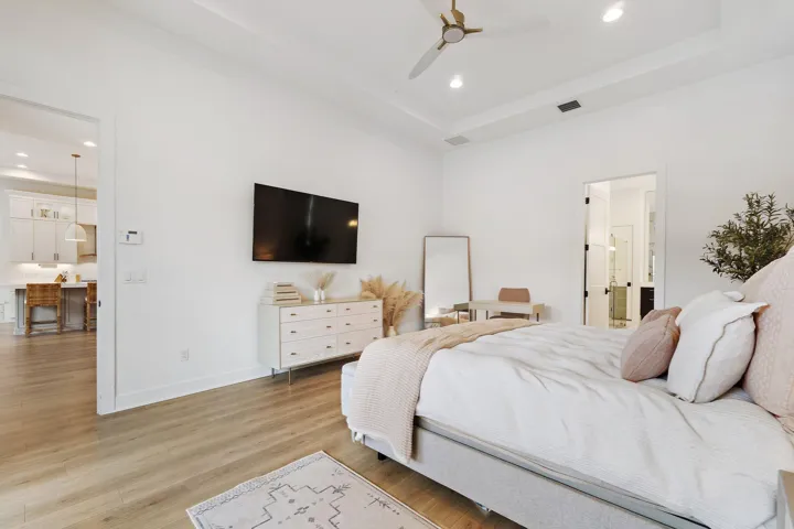 Bedroom with wall-mounted TV, dresser, and mirror