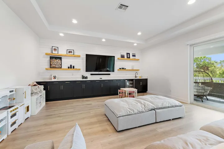 Recreation room with built-in media console, mounted TV, and floating shelves
