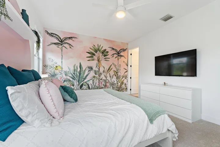 Bedroom with tropical palm mural, mounted TV, and dresser