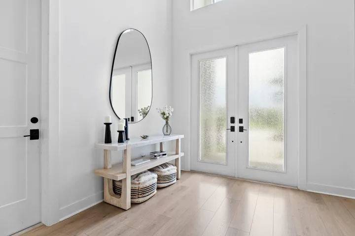 Foyer with round mirror, console table, and French doors to outside