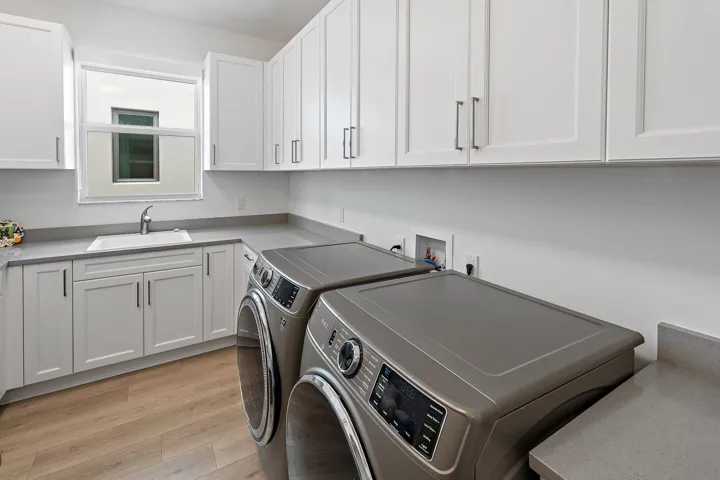Laundry room with white cabinetry and wood flooring