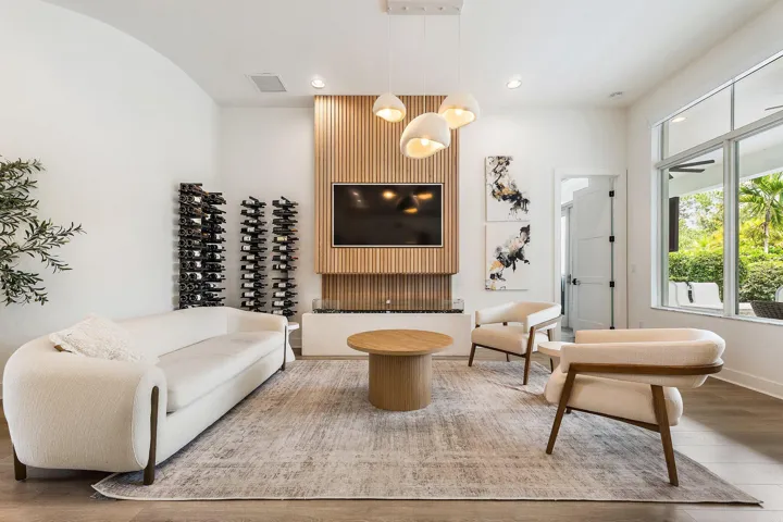 Living room with wood accent wall, wine storage shelving, mounted TV, and round coffee table