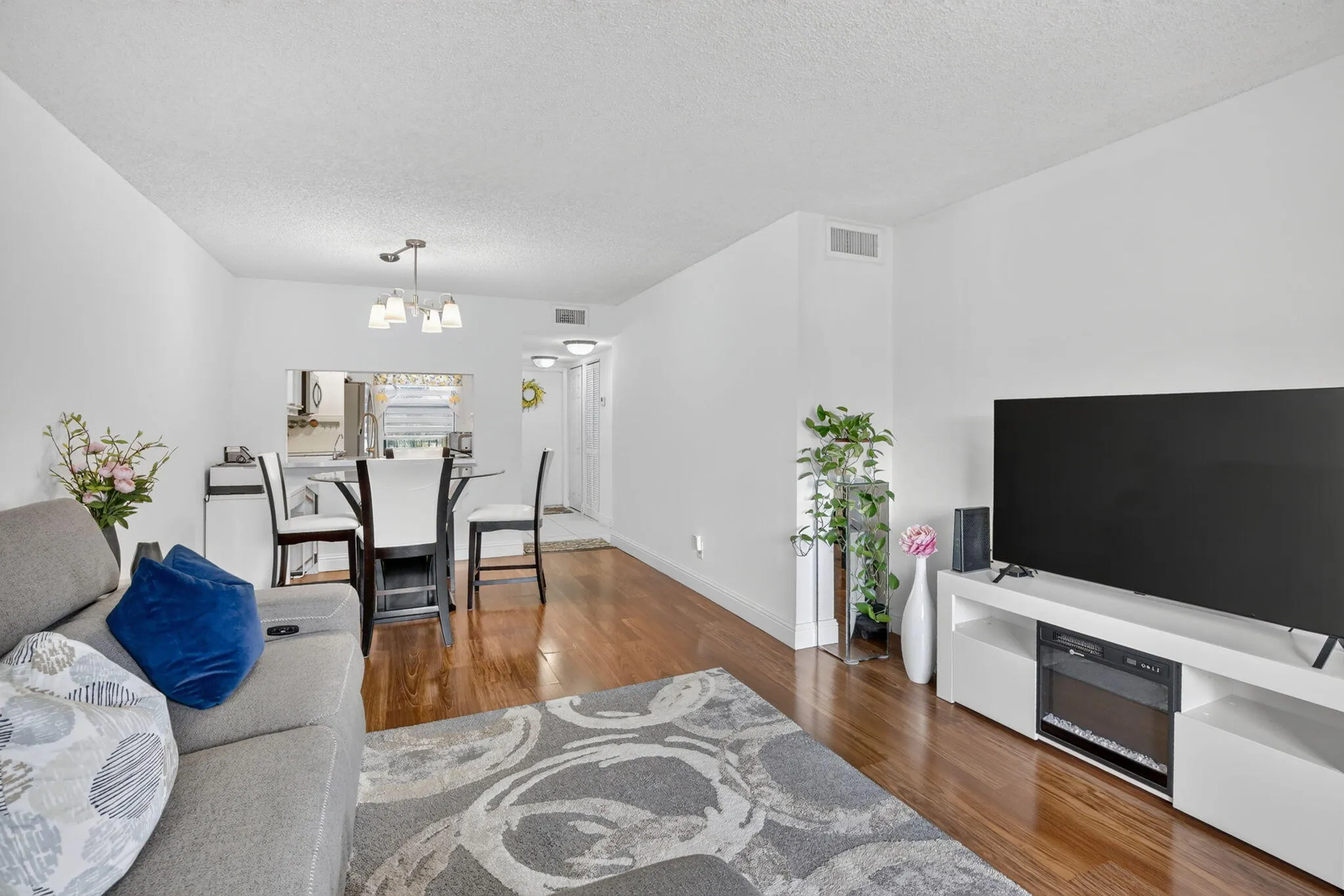 Open-concept living area featuring laminate flooring, white walls, and a pass-through window to the kitchen