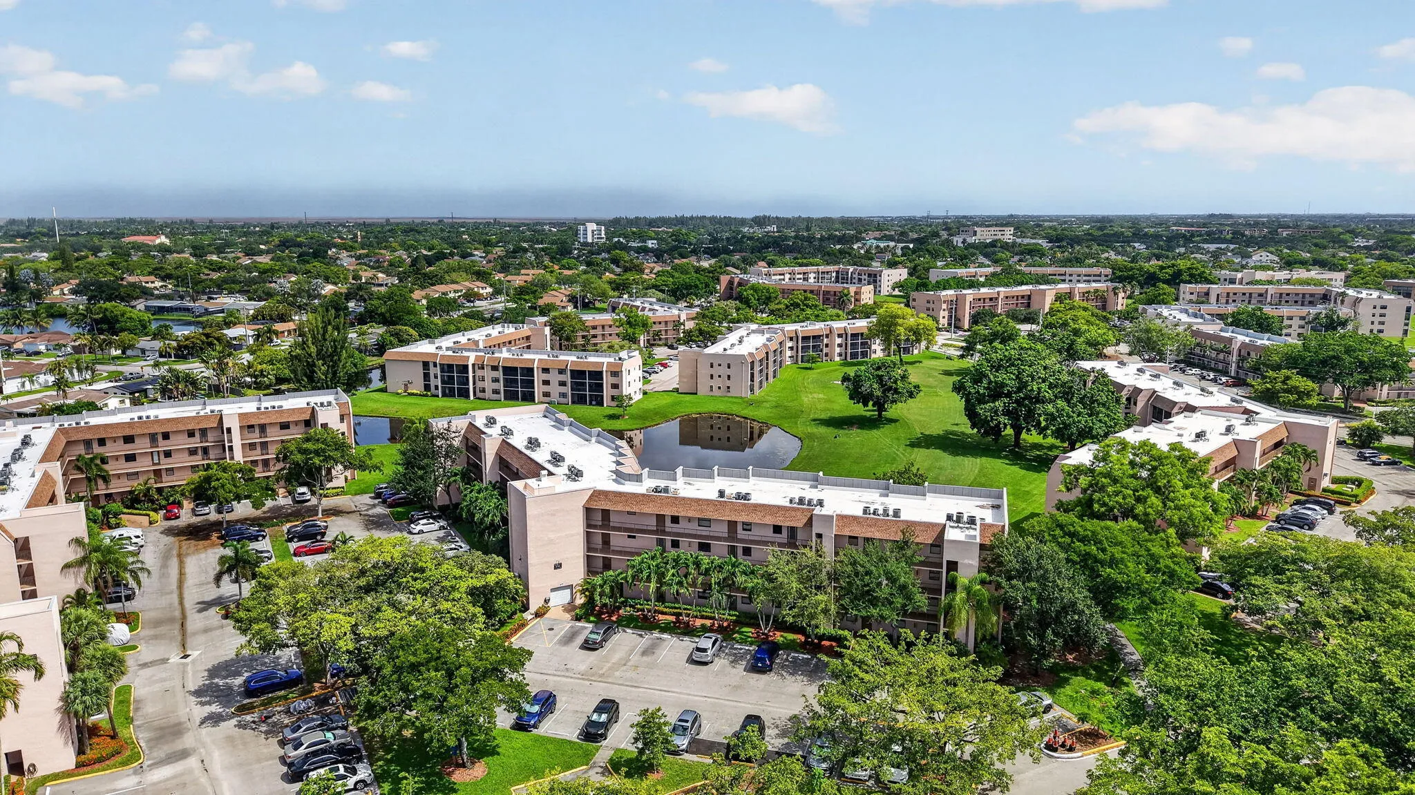 Expansive community featuring multiple residential buildings, abundant green space, a central , mature landscaping, and ample parking