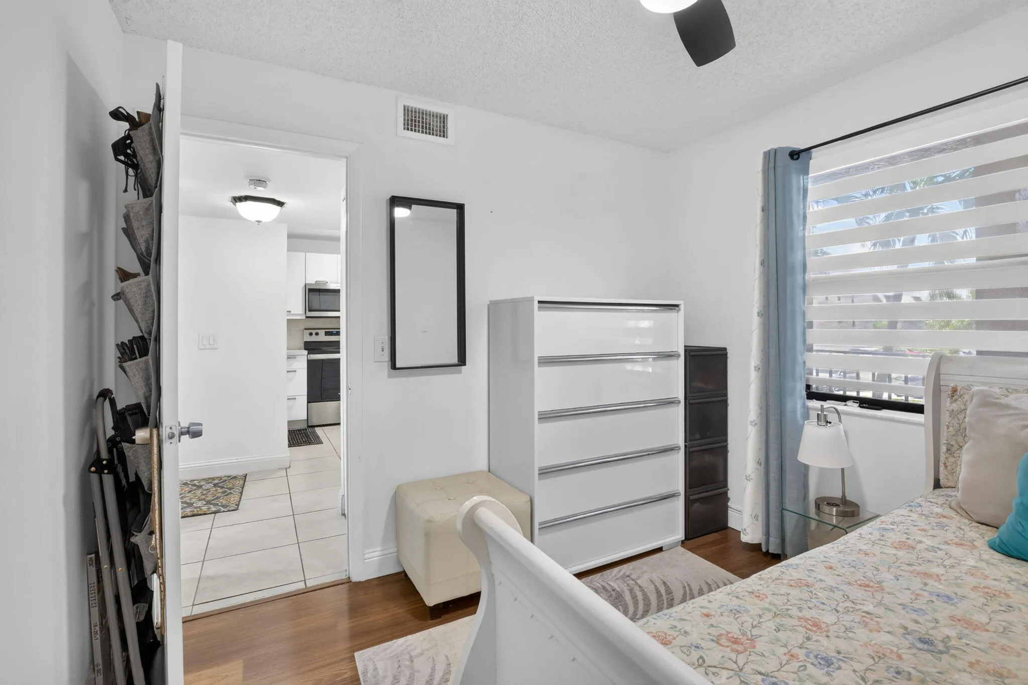 Guest bedroom featuring laminate flooring, white walls, and a ceiling fan
