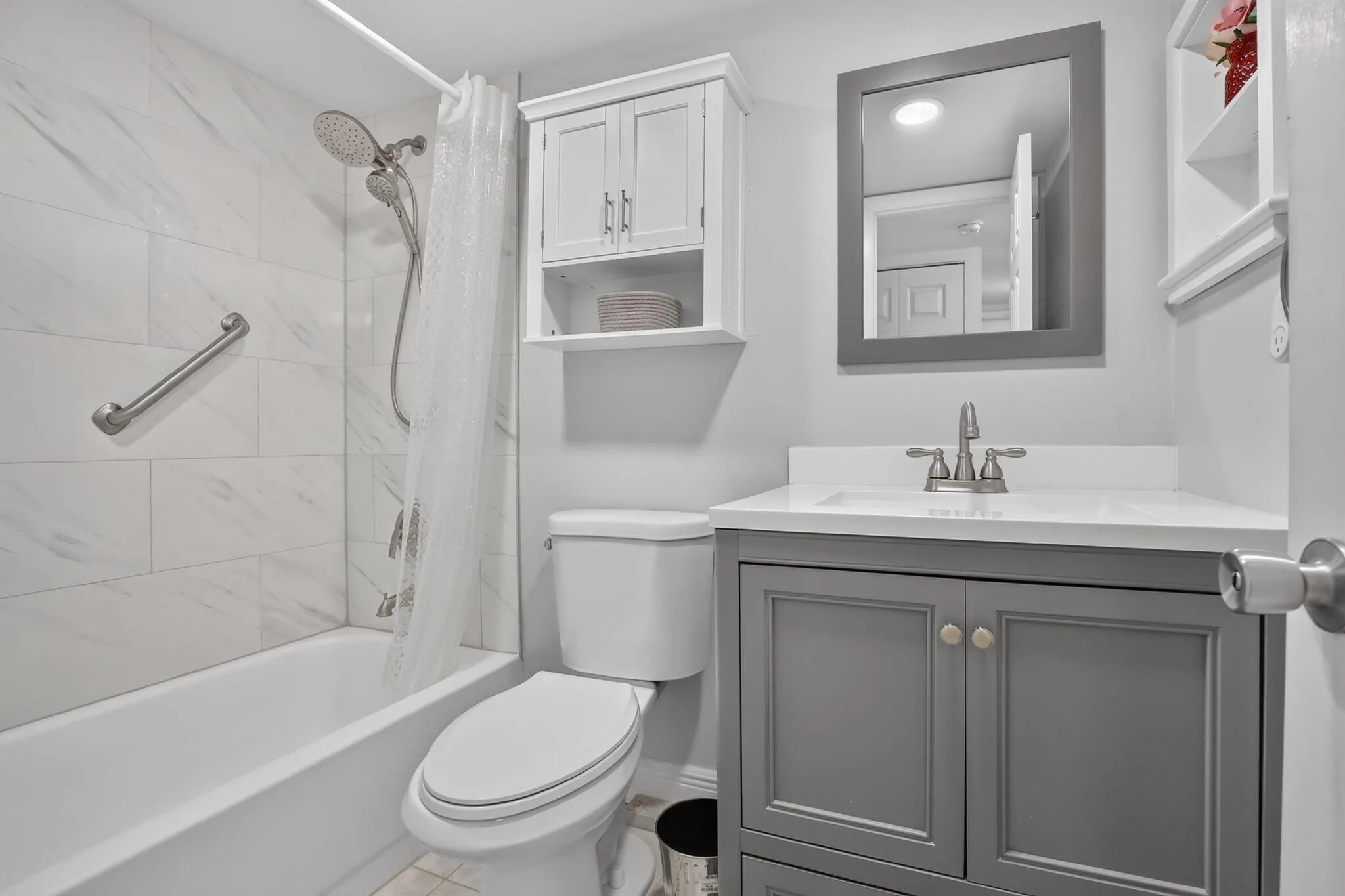 Guest Bathroom featuring a white subway tile shower surround with a grab bar, a flexible shower head, and a white bathtub