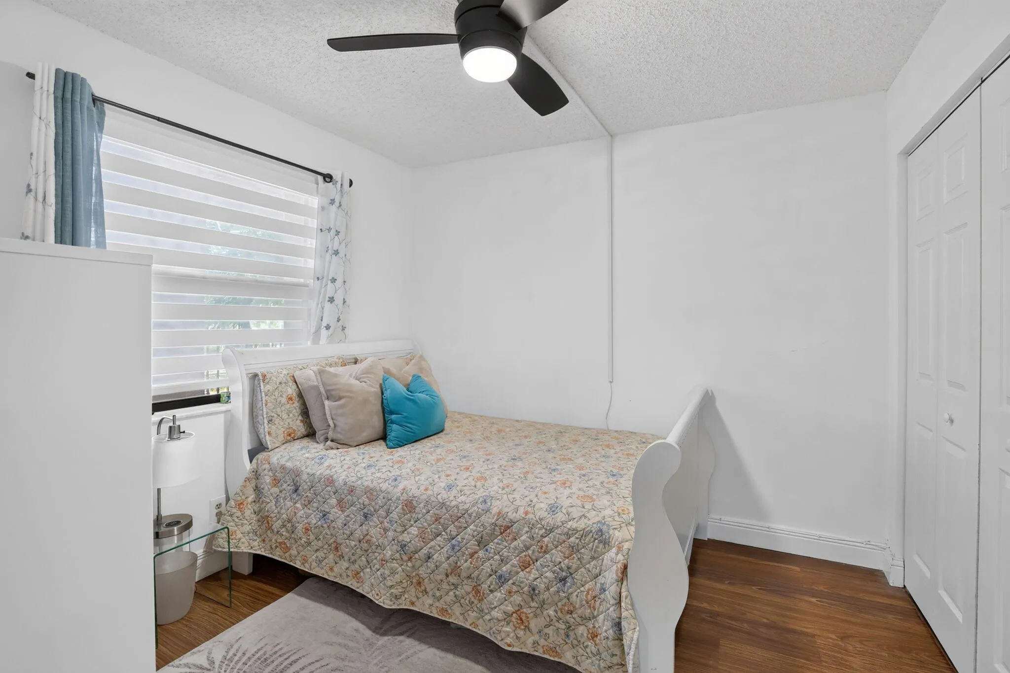 Guest Bedroom featuring laminate flooring, a ceiling fan with integrated lighting, and a window with custom blinds and curtains