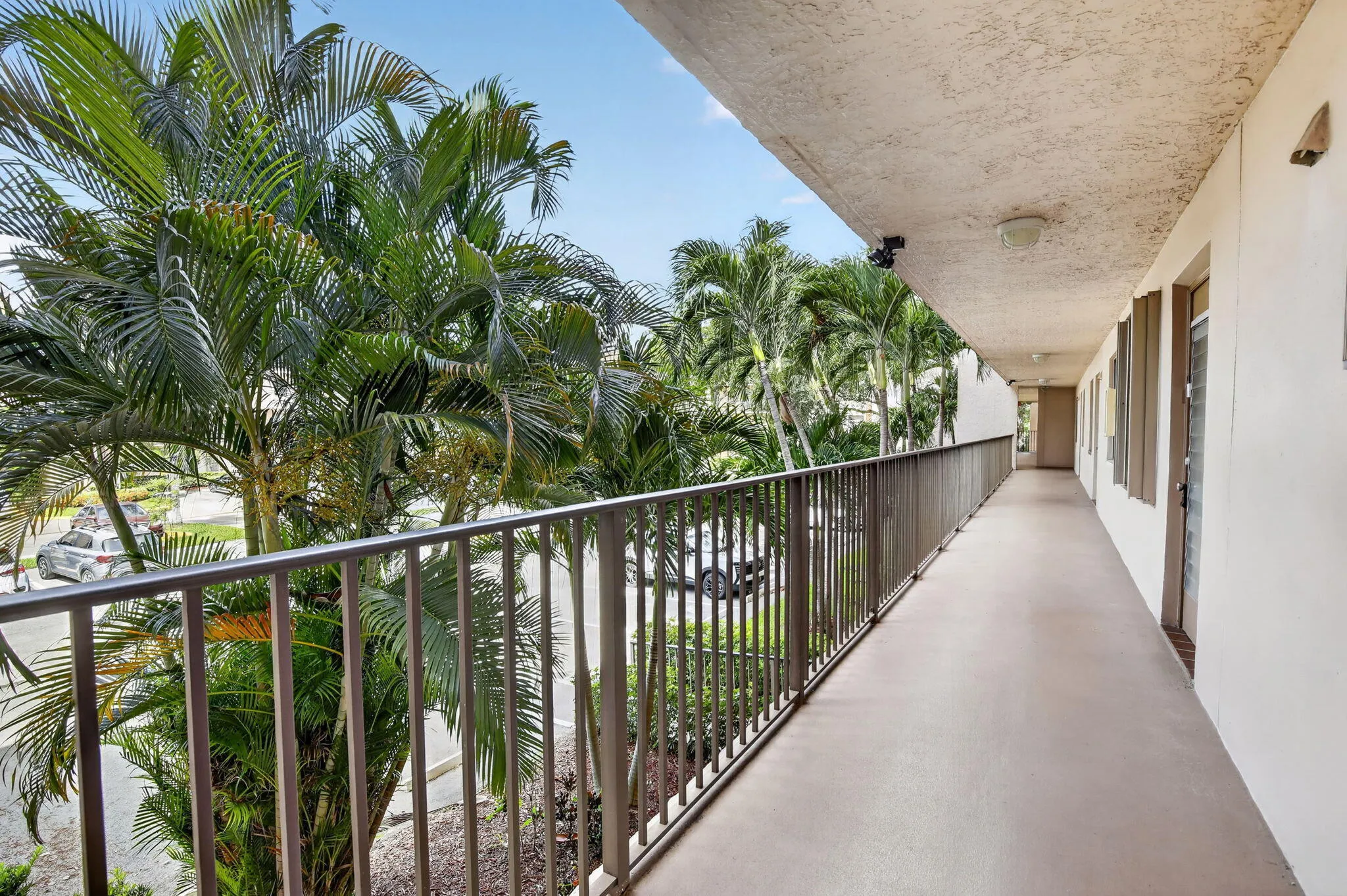 Exterior walkway featuring a metal railing system, and tropical palm tree landscaping