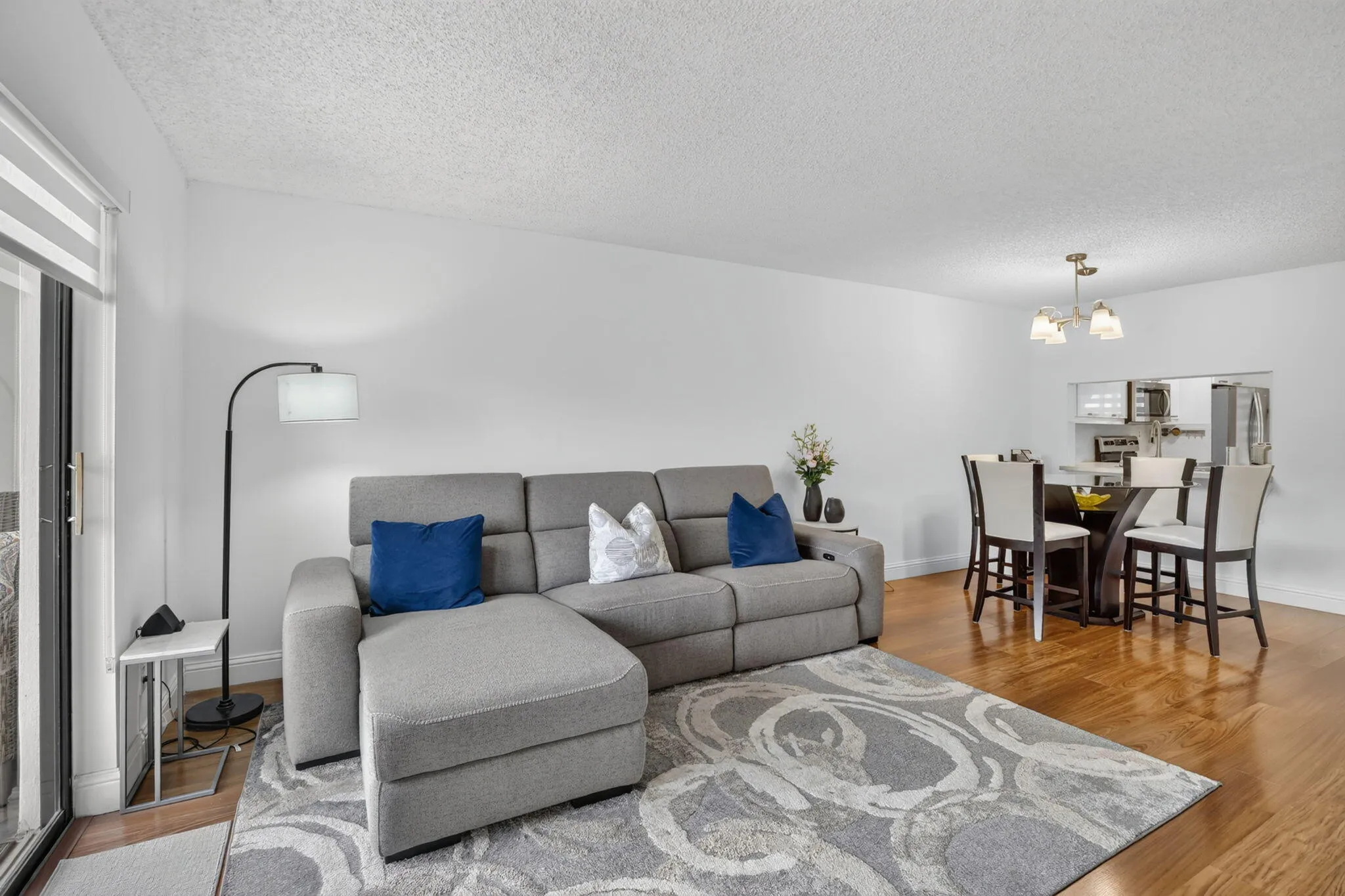 Open-concept living space featuring laminate flooring, white walls, and a textured ceiling