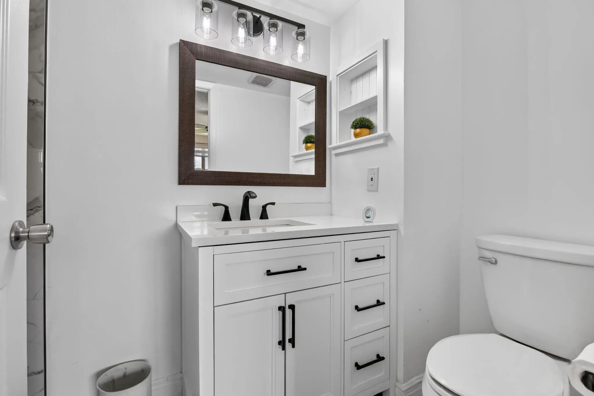 Bathroom vanity featuring a white cabinet with black hardware, a rectangular sink, and a white countertop