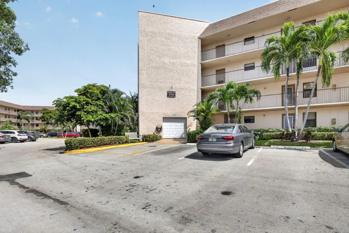 Multi-story building featuring balconies with metal railings, a stucco exterior, and multiple palm trees