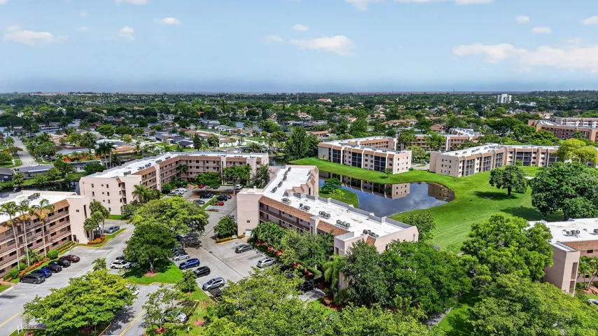 Expansive aerial showcasing multiple residential buildings, surrounded by lush green landscaping and mature trees