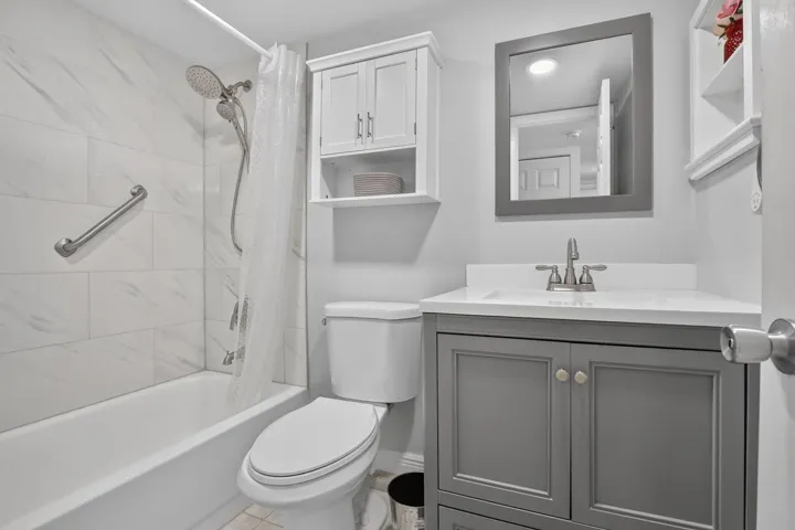Guest Bathroom featuring a white subway tile shower surround with a grab bar, a flexible shower head, and a white bathtub