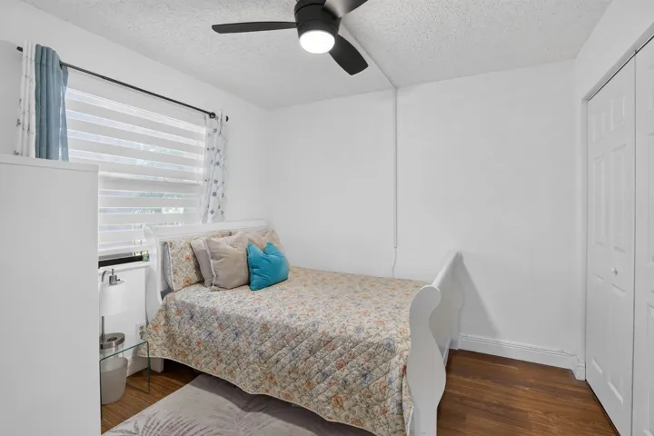 Guest Bedroom featuring laminate flooring, a ceiling fan with integrated lighting, and a window with custom blinds and curtains