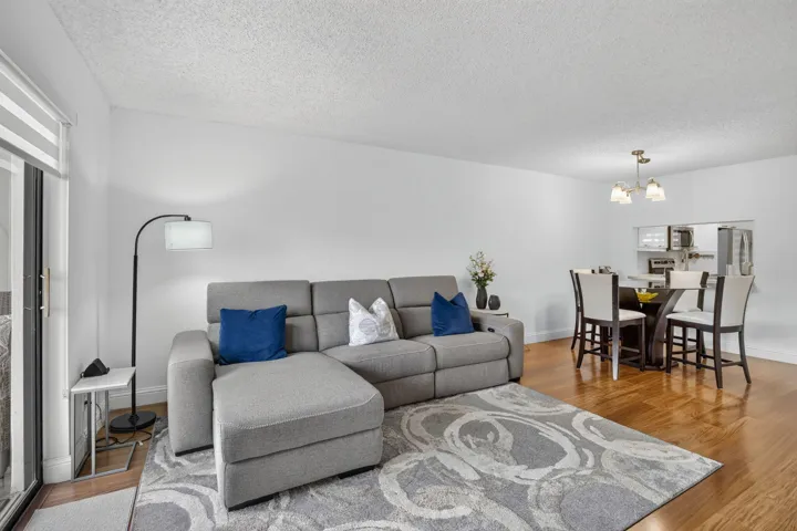 Open-concept living space featuring laminate flooring, white walls, and a textured ceiling