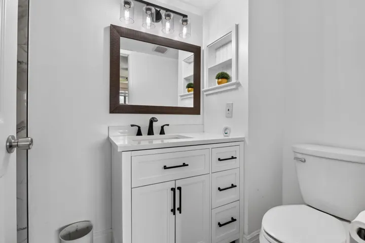 Bathroom vanity featuring a white cabinet with black hardware, a rectangular sink, and a white countertop