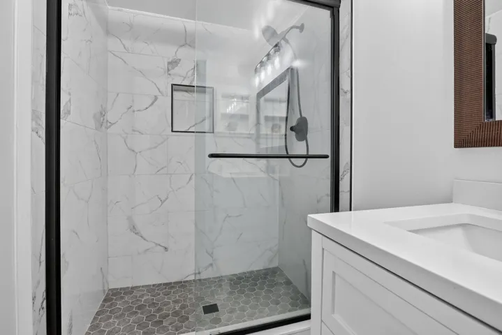 Shower with frameless glass enclosure, black hardware, and an integrated niche