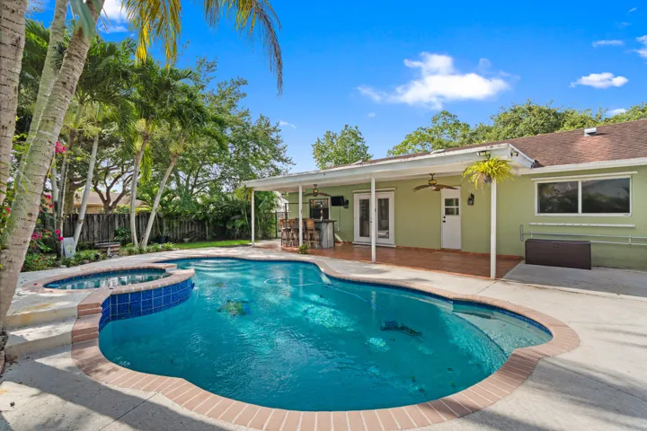 The true centerpiece is the incredible backyard, designed for entertaining with a sparkling pool, covered patio, gazebo, mature tropical landscaping, and abundant yard space.