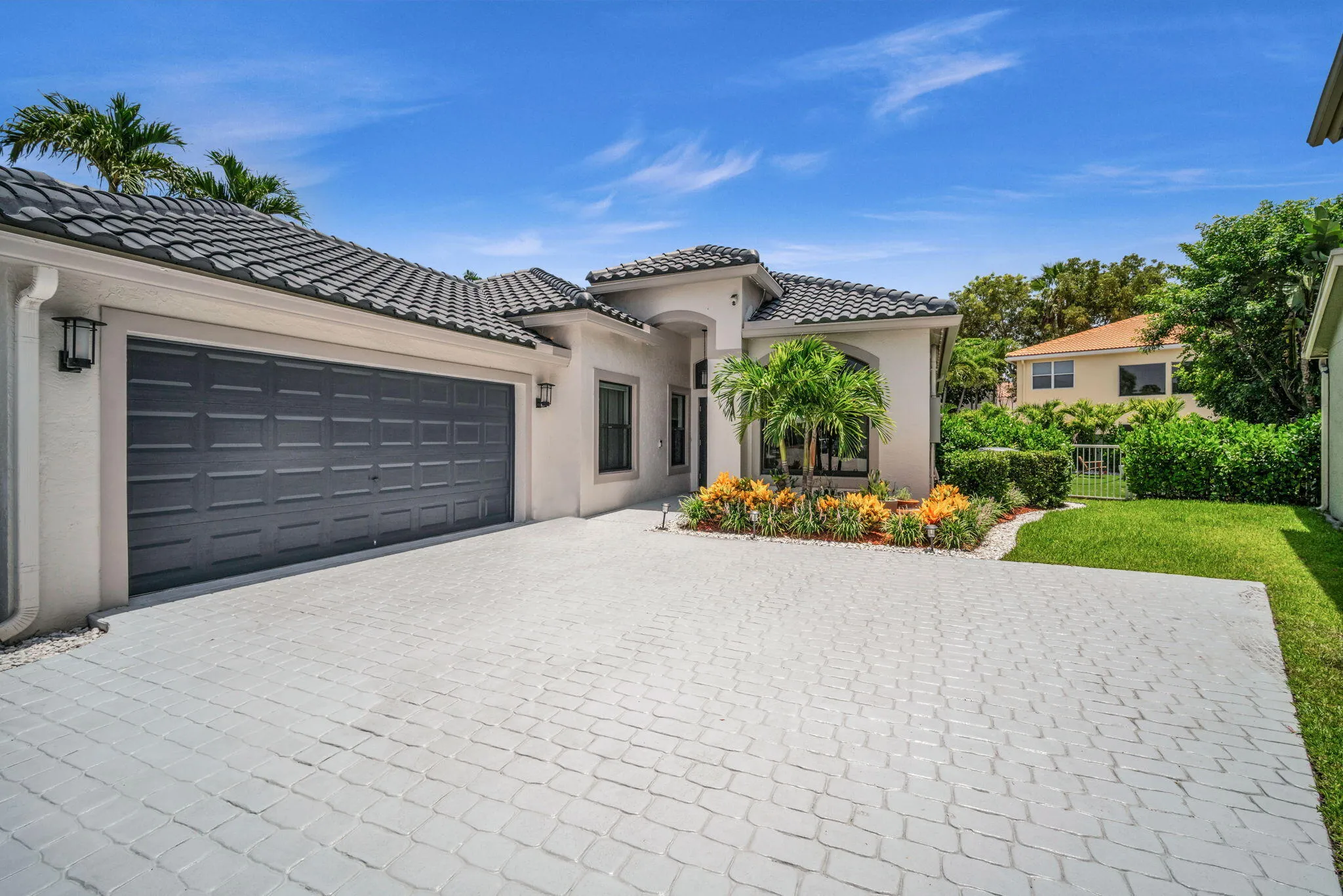 Exterior architecture featuring a tiled roof, stucco finish, and a two-car garage with a gray paneled door