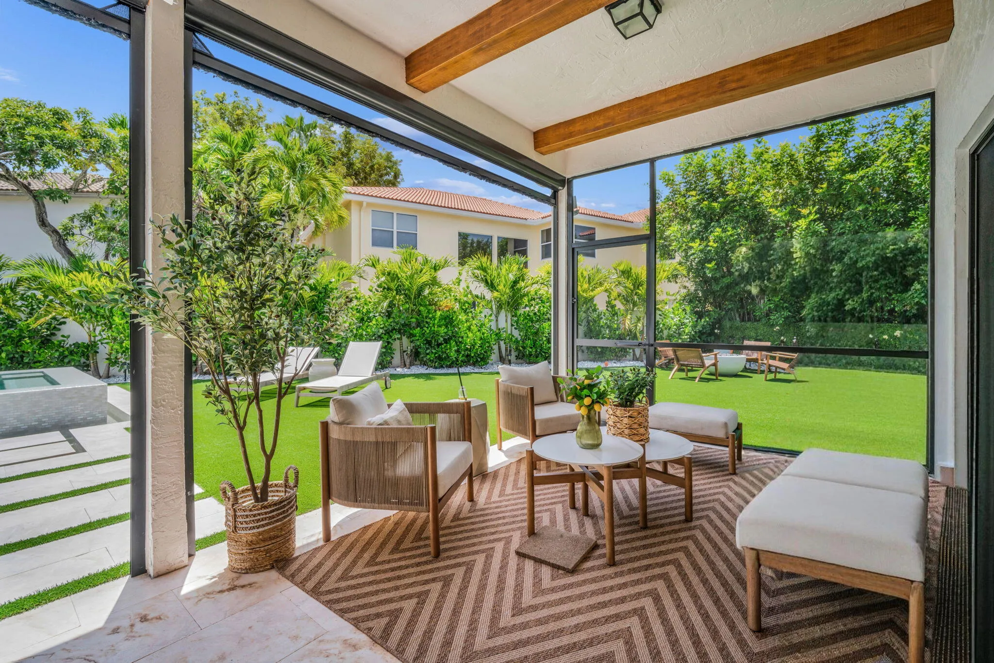 Screened-in patio featuring exposed wood beams, a geometric patterned rug, and natural stone tile flooring