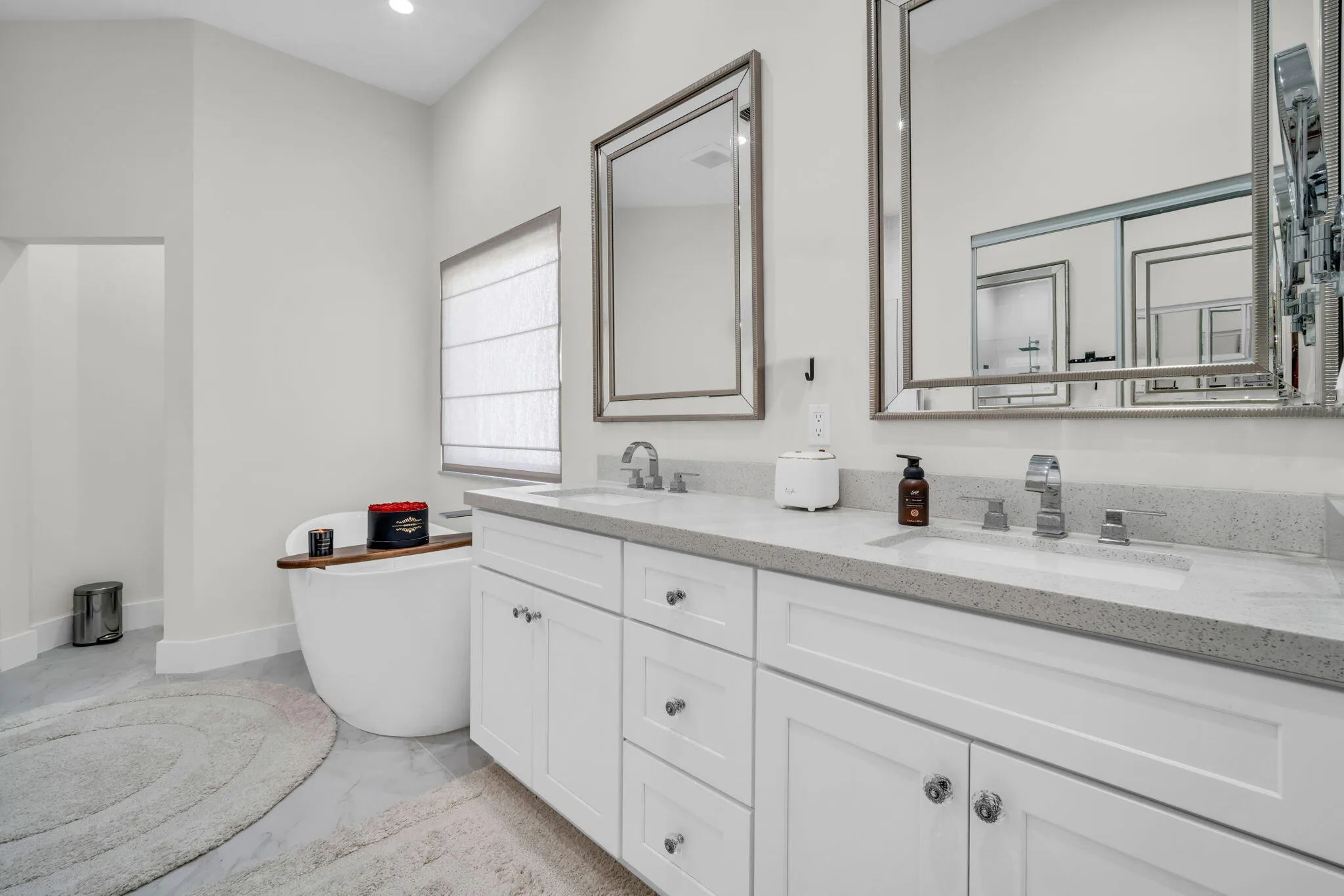 Bathroom featuring a freestanding soaking tub, dual vanities with integrated sinks, and individual framed mirrors