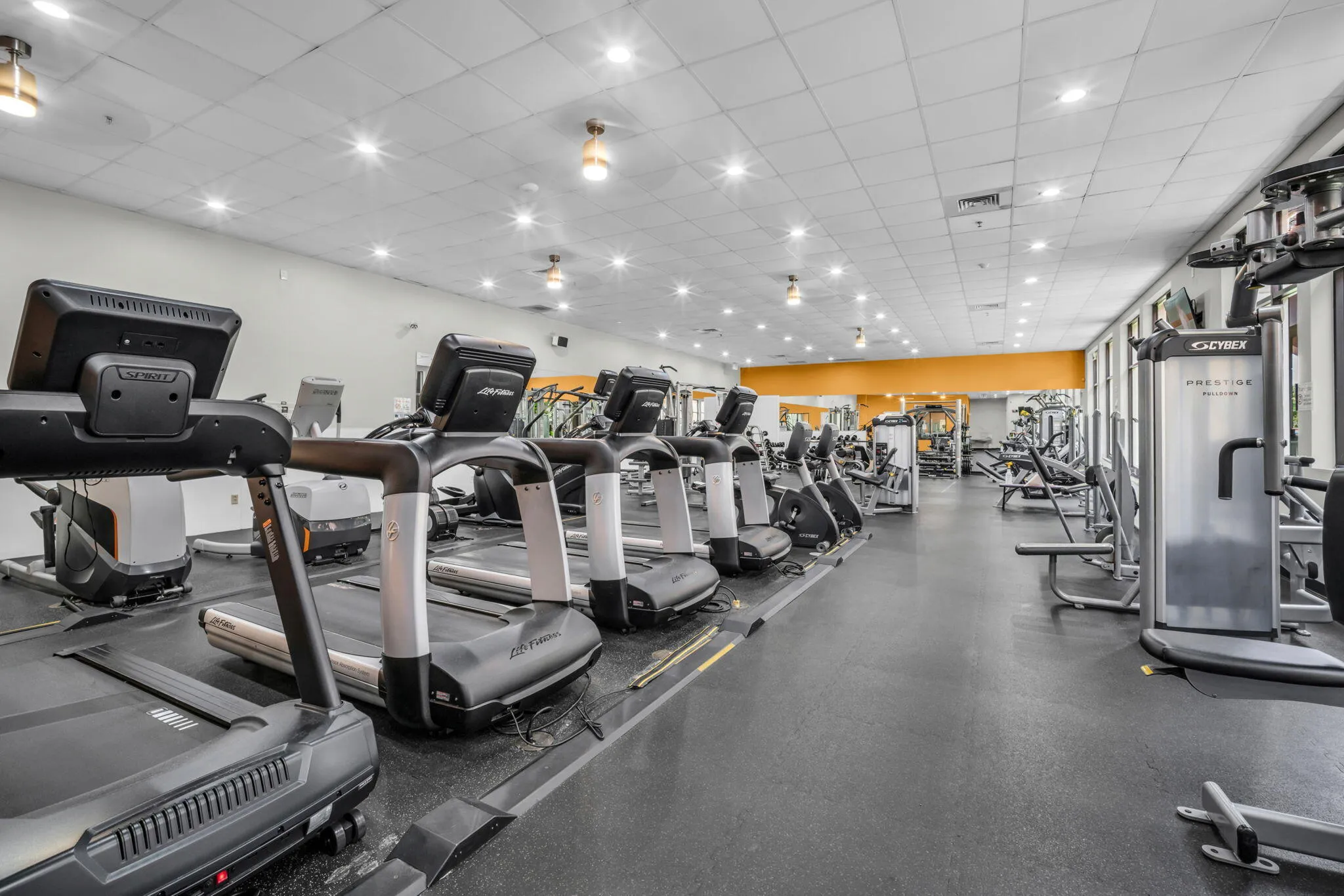 Fitness center featuring rubberized flooring, abundant overhead lighting, a full wall of windows, and various exercise machines