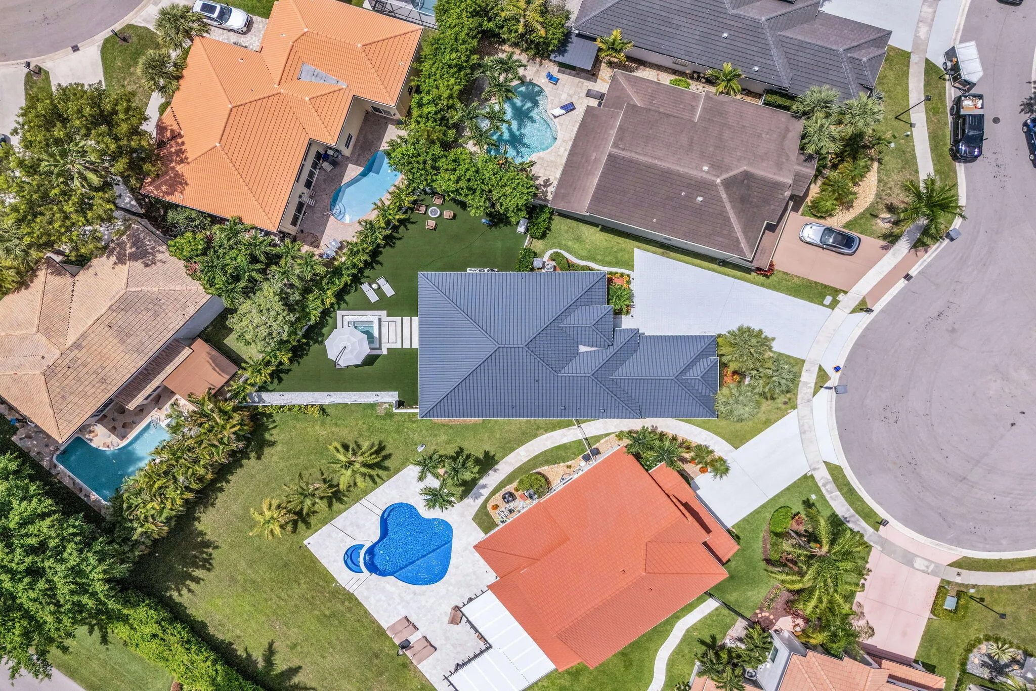 Contemporary-style home featuring a dark gray roof, a spacious driveway, and a private rear yard with a spa