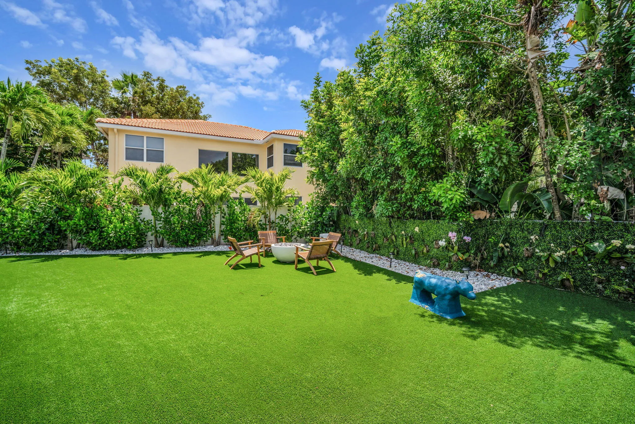 Lush backyard featuring an artificial turf lawn bordered by white gravel