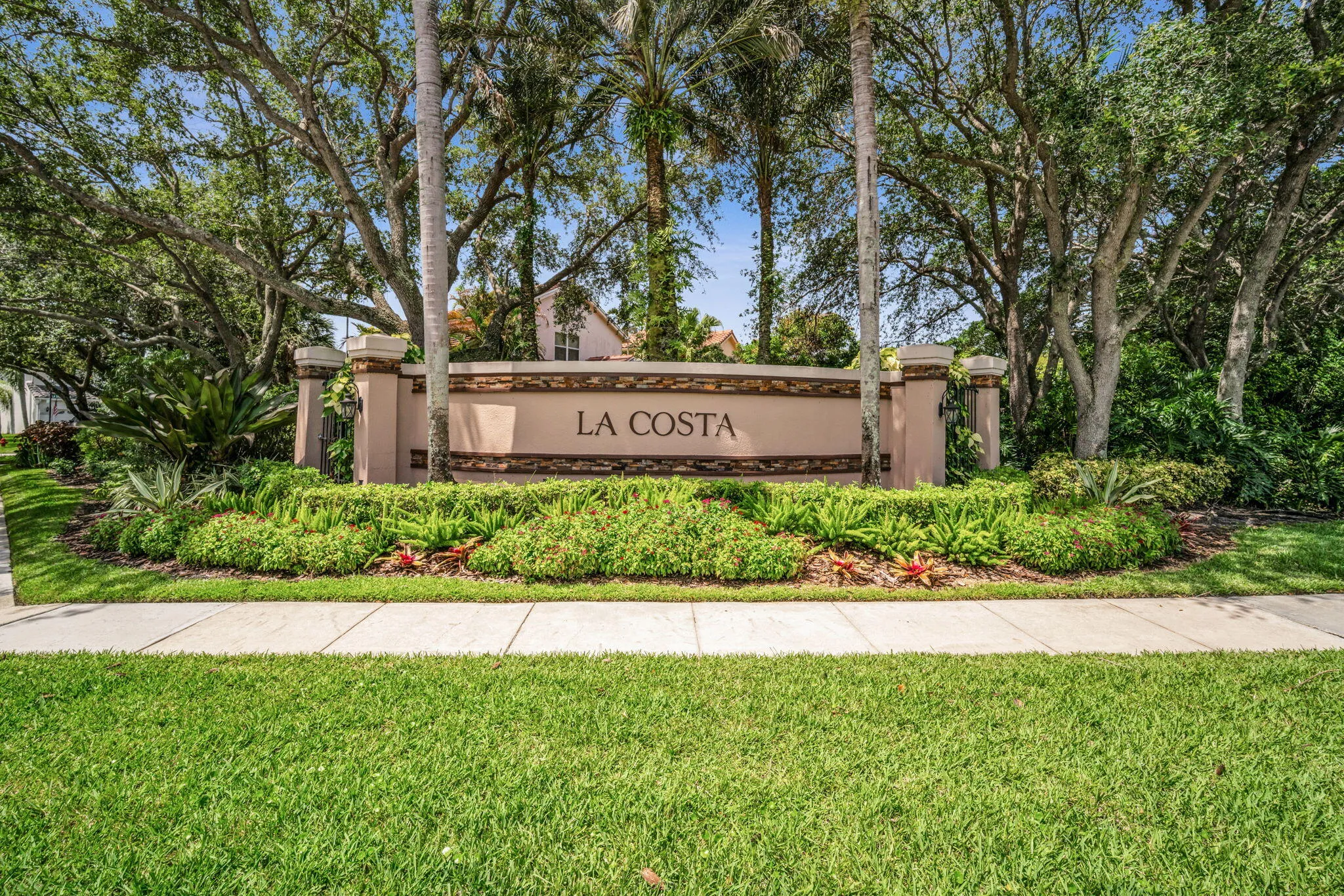 Community entry sign featuring a stone facade and tropical landscaping
