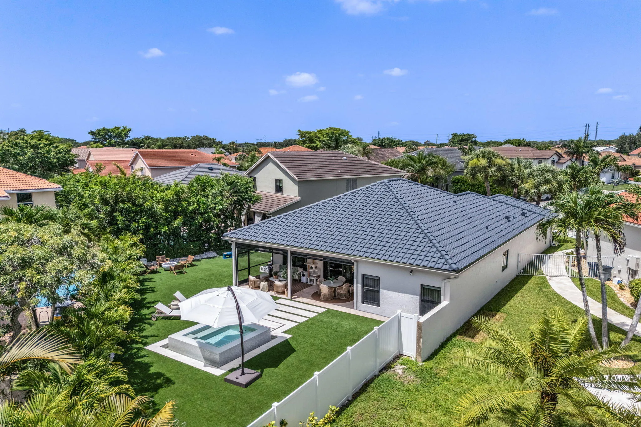 Expansive backyard featuring a hot tub, artificial turf, screened patio, and privacy fencing
