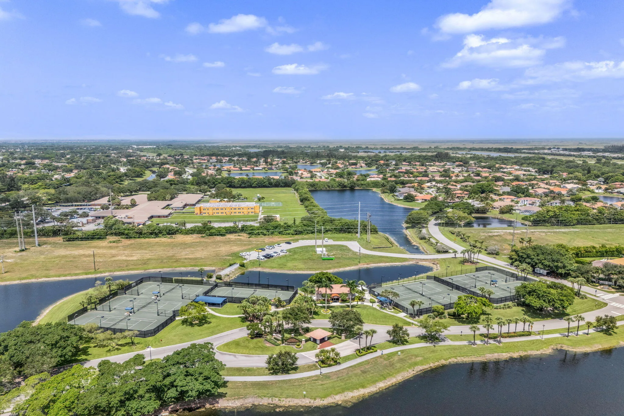 Aerial perspective showcasing multiple tennis courts, surrounding waterways, and a residential community