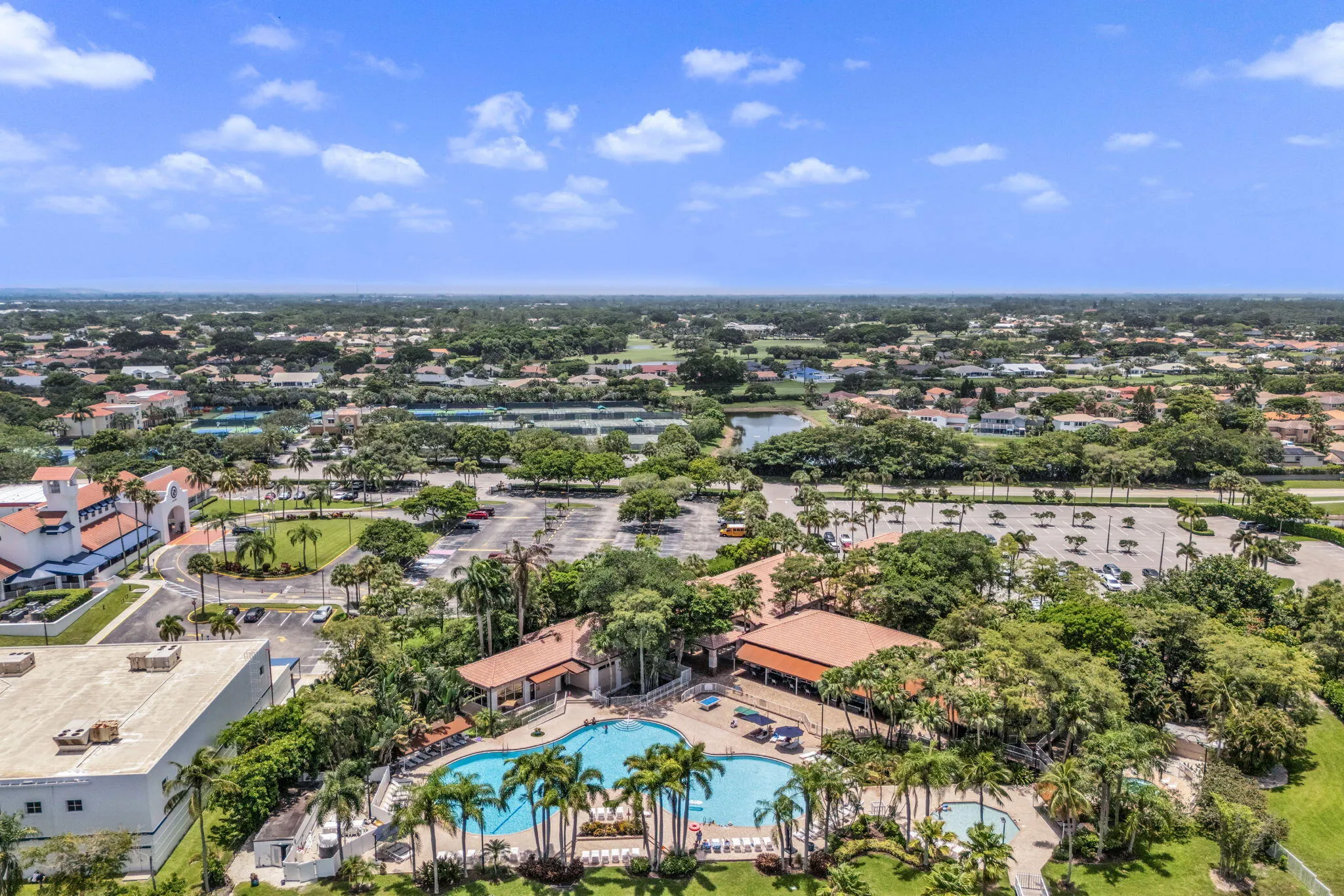Community recreation area featuring multiple pools, surrounding patio space, and mature palm trees