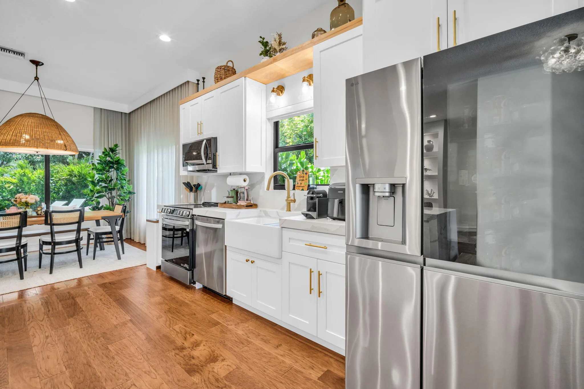 Contemporary kitchen featuring stainless steel appliances, white cabinetry with brass hardware, and wood-finish flooring