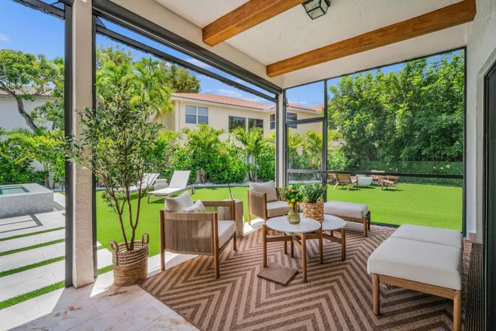 Screened-in patio featuring exposed wood beams, a geometric patterned rug, and natural stone tile flooring