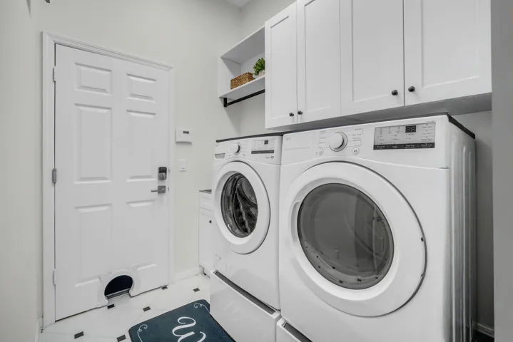 Dedicated laundry area featuring white cabinetry, a built-in shelf, and black and white floor tiling