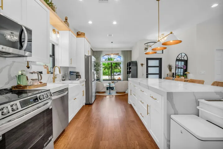 Open-concept kitchen featuring an expansive island with a waterfall countertop and integrated cabinetry